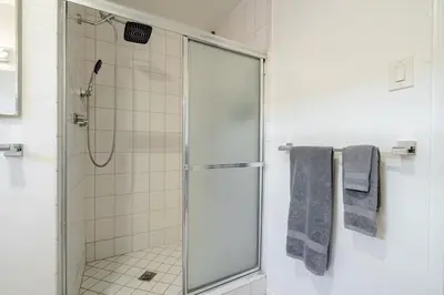 a bathroom with a glass shower with blue towels at Pool Spa Games Peaceful Garden Retreat in Glendale