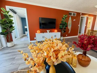 a living room with orange walls and flowers in vases at Oceanfront 2 BR w Pool & Parking 234 in Hermosa Beach