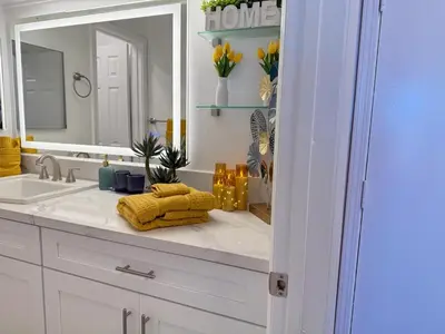 a bathroom with a sink with a mirror and a yellow towel at Oceanfront 2 BR w Pool & Parking 234 in Hermosa Beach