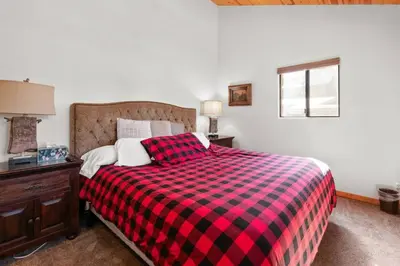 a bedroom with a bed with a red and black plaid blanket at Lakeside Cottage, Charming 3-BDRM Retreat W Hottub in Big Bear Lake