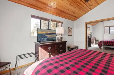 a bedroom with a bed with a red and black blanket at Lakeside Cottage, Charming 3-BDRM Retreat W Hottub in Big Bear Lake