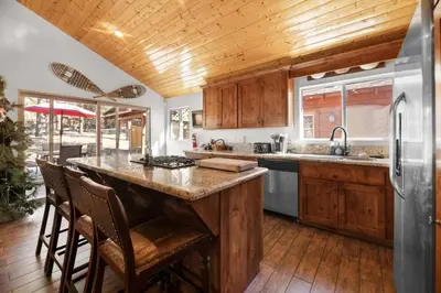 a kitchen with wooden cabinets and a large island with bar stools at Lakeside Cottage, Charming 3-BDRM Retreat W Hottub in Big Bear Lake