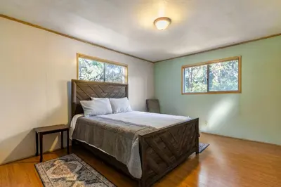 a bedroom with a bed and two windows at Cozy 2BR Retreat Near Lake Grego with Mountain Views in Crestline
