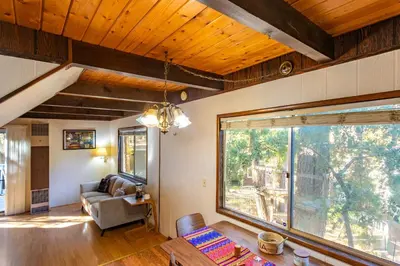 a living room with a couch and a large window at Cozy 2BR Retreat Near Lake Grego with Mountain Views in Crestline