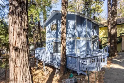 a blue tiny house between two trees at Cozy 2BR Retreat Near Lake Grego with Mountain Views in Crestline