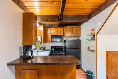 a kitchen with wooden cabinets and a black refrigerator at Cozy 2BR Retreat Near Lake Grego with Mountain Views in Crestline