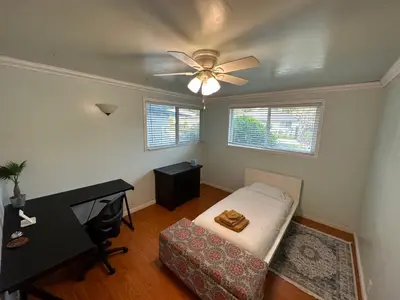 a room with a bed and a desk and a ceiling fan at Suburban oasis home in Monterey Park