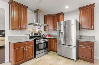a kitchen with wooden cabinets and a stainless steel refrigerator at Spacious Retreat w Large Kitchen & Outdoor Patio in Pasadena