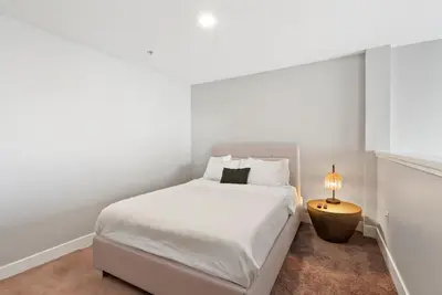 a white bedroom with a bed and a lamp at Spacious Loft- Hollywood Free Pool, Parking, Gym in Los Angeles