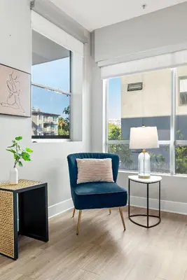 a living room with a blue chair and a lamp at Spacious Loft- Hollywood Free Pool, Parking, Gym in Los Angeles