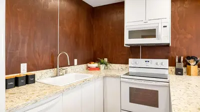 a kitchen with white appliances and wooden walls at 2 Units in Prime Hollywood Location Chic Renovated 1BDRs w Patio AvantStay in Los Angeles