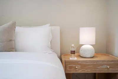 a bed with a night stand with a lamp and a bottle of alcohol at The Surf Lodge Villa in Malibu
