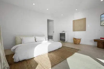 a white bedroom with a large bed and a fireplace at The Surf Lodge Villa in Malibu