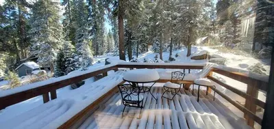 a deck with two chairs and a table in the snow at Blue Jay's Nest Sequoia Cabin in Ponderosa, CA in Ponderosa