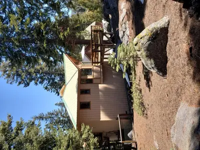 a house built into a cliff with a tree at Blue Jay's Nest Sequoia Cabin in Ponderosa, CA in Ponderosa