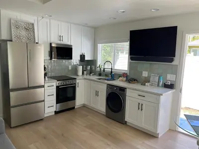 a kitchen with white cabinets and a sink and a refrigerator at Private guest cottage in Long Beach