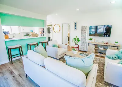 a living room with white couches and a kitchen at Beach House Steps to the Sand! in Manhattan Beach