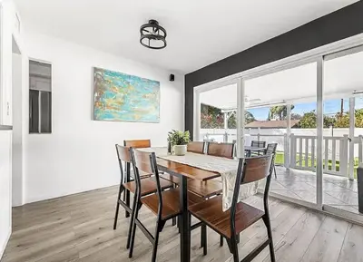 a dining room with a table and chairs and windows at Love & LuxuryHeart Shaped Pool Paradise in Los Angeles
