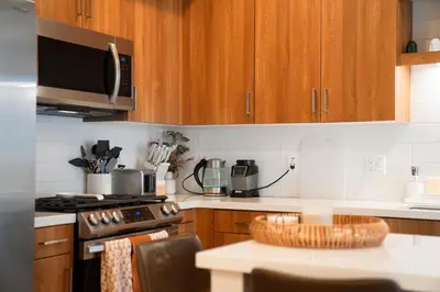 a kitchen with wooden cabinets and a stove top oven at Heart of North Hollywood 2 bed Apt FREE parking, hot tub, pool, gym in Garnsey