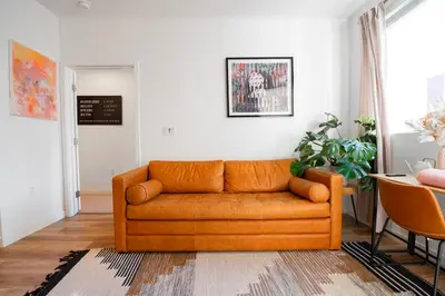 an orange couch in a living room with a table at Heart of North Hollywood 2 bed Apt FREE parking, hot tub, pool, gym in Garnsey
