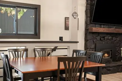 a dining room with a table and chairs and a fireplace at Timber Wolf Tavern - Walk to Slopes, Game Room, Pool Table, BBQ in Big Bear Lake
