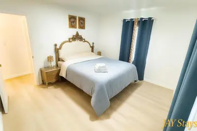 a bedroom with a white bed with blue curtains at Newly renovated, warm home with 4 bedrooms, 14 miles from Disney in Whittier