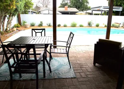 a table and chairs sitting next to a pool at Cozy 3BR Home With Pool, Yard, Garage, and 80 inch TV! in Van Nuys