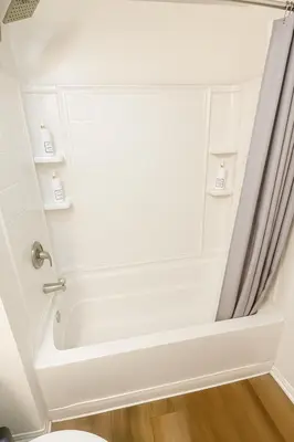 a white bath tub in a bathroom with a shower curtain at Ocean Breeze Marina Suites with Pool, Gym & Hot Tub in Los Angeles