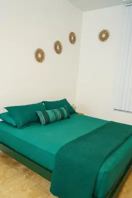 a bed with a green comforter in a bedroom at Ocean Breeze Marina Suites with Pool, Gym & Hot Tub in Los Angeles