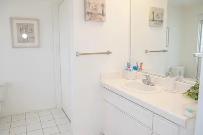 a white bathroom with a sink and a mirror at Ocean Breeze Marina Suites with Pool, Gym & Hot Tub in Los Angeles