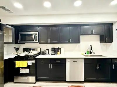 a kitchen with black cabinets and white counter tops at GilmoreOne in Van Nuys