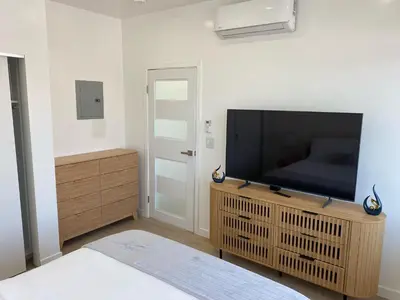 a bedroom with a flat screen tv on a wooden entertainment center at Pacific Coast Suites - Oceanfront Living in Los Angeles