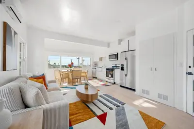 a white living room with a couch and a table at Pacific Coast Suites - Oceanfront Living in Los Angeles