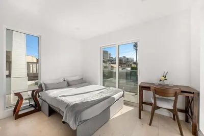 a bedroom with a bed and a table and a window at Pacific Coast Suites - Oceanfront Living in Los Angeles