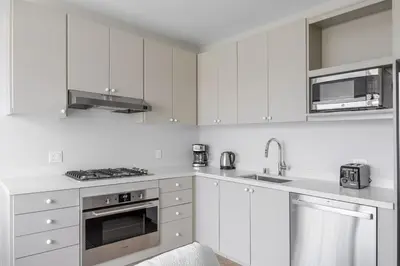 a white kitchen with white cabinets and stainless steel appliances at Blueground Downtown elevator nr parks LAX-1252 in Los Angeles