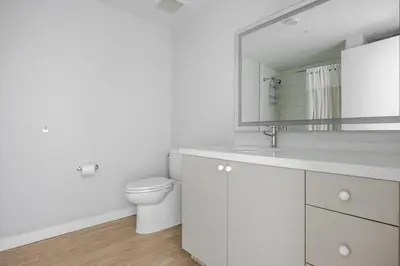 a white bathroom with a toilet and a mirror at Blueground Downtown elevator nr parks LAX-1252 in Los Angeles