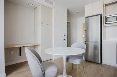 a kitchen with a table and chairs and a refrigerator at Blueground Downtown AC elevator nr parks LAX-1253 in Los Angeles