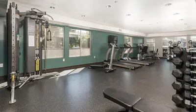 a gym with several treadmills and machines in it at Blueground Glendale pool AC nr Americana LAX-1319 in Glendale