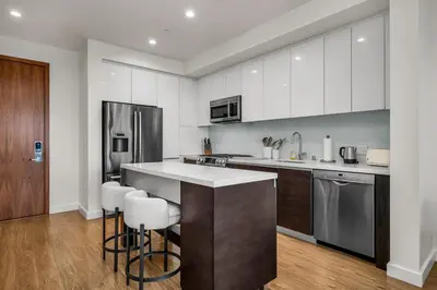 a kitchen with white cabinets and a counter with bar stools at The Sky Gem in Los Angeles