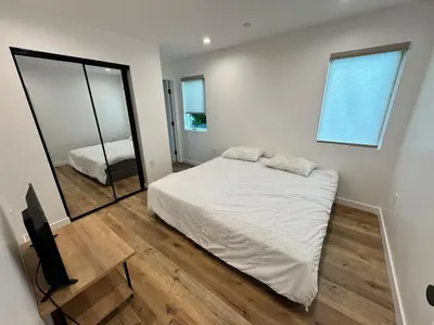 a bedroom with a white bed and a mirror at Los Angeles Central Town House in Los Angeles