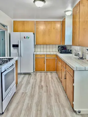 a kitchen with white appliances and wooden cabinets at Quaint Mid-Century Cottage by the Coast in Ventura