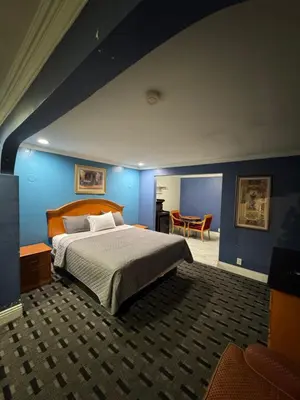 a bedroom with a bed and a blue wall at Sunset Inn & Suites in Gardena
