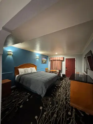 a hotel room with a bed and a desk at Sunset Inn & Suites in Gardena