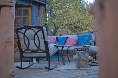 a porch with a bench and chairs on a deck at Ray's Dear Cottage in Wrightwood