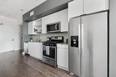 a kitchen with white cabinets and a stainless steel refrigerator at Hollywood 1bdr Comfort with Pool, Gym, Free Parking in Los Angeles