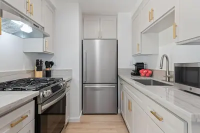 a kitchen with white cabinets and a stainless steel refrigerator at Jasmine Hideaway and Newly Renovated in Summerland