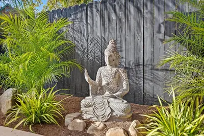 a statue sitting in a garden in front of a fence at Jasmine Hideaway and Newly Renovated in Summerland