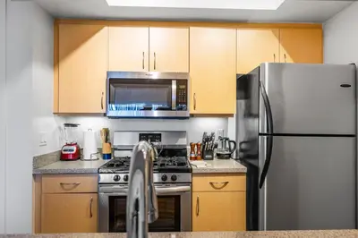 a kitchen with wooden cabinets and a stainless steel refrigerator at 12 Best Location Cozy Apartment in Los Angeles