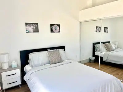 a bedroom with a large white bed and a mirror at Newly Gated Stylish Steps to Hollywood 2B2B in North Sherman Way
