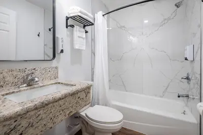 a white bathroom with a sink and a toilet and a tub at La Casita Inn in Wilmington